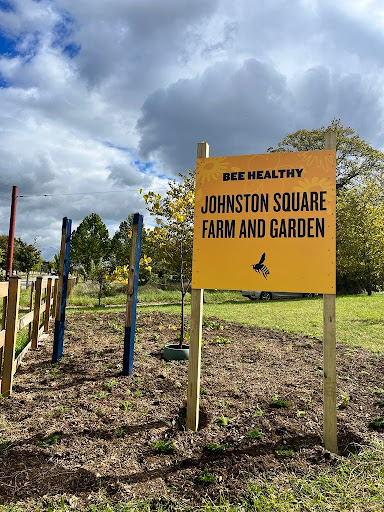 A big yellow sign posted in a garden bed reads, 